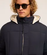 Campera puffer de hombre reversible, con diseño acolchado, cuello alto, capucha y cierre frontal.
