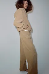 Pantalón de tiro medio color beige, de pierna ancha y corte recto. Cuenta con cintura elástica ajustable con cordones y bolsillos frontales.