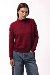 Sweater de tejido de punto con textura de pequeños relieves circulares, cuello redondo y mangas largas. Presenta un calce relajado con puños y ruedo acanalados.