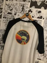 Remera blanca con mangas negras y cuello redondo. Estampado frontal con el logo de Capsule Corp de la serie Dragon Ball.