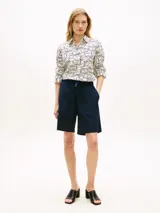 Camisa Tommy Hilfiger de corte amplio confeccionada en lino puro, con diseño estampado de líneas geométricas en azul sobre base blanca. Presenta cuello inglés, cierre frontal abotonado, mangas largas con puños abotonados y logo bordado en el pecho.
