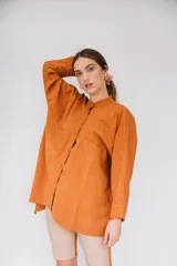 Camisa de sarga color mostaza, de diseño irregular con los costados más largos, mangas largas y corte amplio.