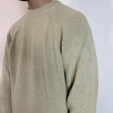 Sweater verde oliva de tejido grueso con cuello alto y mangas raglán. Corte holgado.