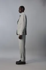 Blazer slim fit de color gris, con cuello de solapas de muesca, cierre frontal de dos botones, bolsillos laterales con solapa y bolsillo de vivo en el pecho. Presenta mangas largas con botones en los puños y aberturas en la espalda.