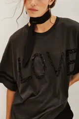 Remera de algodón y modal con cuello redondo, mangas cortas con detalle de rayas laterales y estampa frontal con la palabra LOVE bordada en lentejuelas.