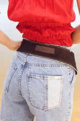 Cinto faja de cuero con estampado de vaca en blanco y negro, con hebilla metálica rectangular.