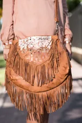 Cartera bandolera de cuero marrón con flecos colgantes y detalles pintados a mano en la solapa.