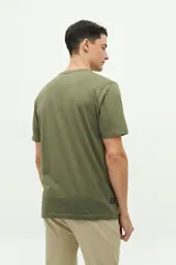 Remera verde militar de manga corta con cuello redondo y estampado frontal con el texto "Brookfield The Emporium of Postmodern Activity No 1001 Torino | 1971".