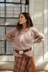 Buzo de lana color rosado, con cuello redondo, mangas largas y diseño holgado.