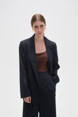 Blazer de corte holgado con diseño de rayas verticales, cuello solapa y cierre frontal con un botón. Presenta bolsillos laterales con solapa y mangas largas.