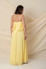 Vestido largo strapless de gasa plisada color celeste, con volados en el busto y corte en la cintura.