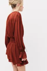 Vestido corto marrón de tejido drapeado con cuello redondo, manga larga abullonada y detalle de nudo en la cintura con tiras colgantes.