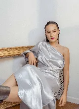 Vestido plateado de satén elastizado, con un hombro descubierto, manga corta abullonada y lazo en la cintura.