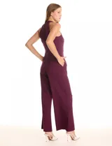 Enterito largo de crepe color rojo, con escote halter anudado y pierna ancha. Presenta bolsillos delanteros y abertura en la espalda con cierre invisible y botón.