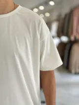 Remera blanca oversize de manga corta, con diseño texturado de líneas finas verticales y cuello redondo.