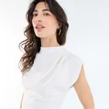 Camiseta sin mangas de color blanco, con cuello alto y diseño asimétrico de corte fluido.