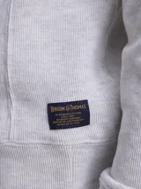 Fleece de algodón color gris melange, con cuello alto y cierre frontal parcial. Diseño de manga larga con puños y ruedo acanalados.