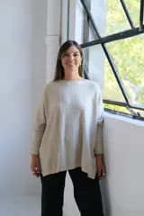 Sweater de punto con hilo lurex color beige, de corte holgado, cuello redondo y mangas largas con puños ajustados. Presenta un diseño con líneas verticales en relieve y aberturas laterales en el ruedo.