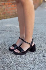 Sandalias de cuero negro con textura reptil, taco cuadrado y plataforma baja. Tiras cruzadas en el empeine con una franja central charolada y tira ajustable con hebilla en el talón.