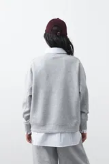 Buzo de manga larga color marrón chocolate, con silueta relajada, hombros caídos y diseño minimalista. Confeccionado en tejido suave con caída fluida.