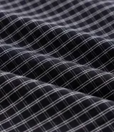 Pijama corto masculino confeccionado en algodón, compuesto por una remera lisa de manga corta con cuello redondo en color gris melange y una bermuda con estampado integral a cuadros oscuros con cintura elástica.