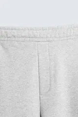 Pantalón jogger de corte relajado y pernera ancha, confeccionado en tejido de algodón con interior perchado. Cuenta con cintura elástica ajustable mediante cordón interior, bolsillos laterales y un bolsillo trasero de plastrón.