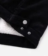 Campera de pana negra con cuello de sherpa blanco, cierre frontal por cremallera y bolsillos delanteros con solapa y botón. Presenta forro interno de sherpa para mayor calidez.