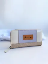 Billetera de cuero color lila, beige y blanco, con cierre metálico y monedero interno.