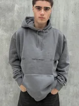 Canguro gris con capucha ajustable con cordones, bolsillo tipo canguro y estampado frontal con la leyenda "CRAFTED PROJECT" y el logo de la marca.