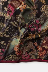 Pañuelo cuadrado de tejido satinado con estampado floral y botánico en tonos marrones, violetas y amarillos. Presenta un borde con línea a contraste.