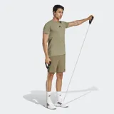 Short de entrenamiento Adidas, color verde oliva, con cintura elástica y cordón ajustable. Presenta logo de la marca en el lateral y bolsillos frontales con cierre.