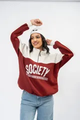 Buzo de estilo deportivo con diseño de bloques de color en blanco y bordó. Presenta cuello alto con medio cierre frontal, mangas largas con puños acanalados y estampado gráfico frontal con la palabra Society.
