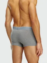 Pack de tres bóxers Diesel, uno negro con elástico blanco y logo, y dos con estampado de camuflaje en tonos grises y negros.