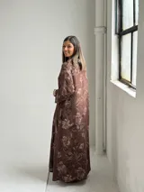 Vestido largo marrón de lino con estampado floral, cuello redondo holgado y mangas tres cuartos.