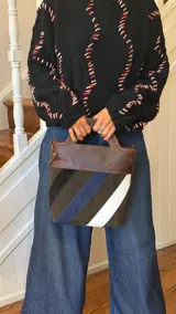 Matera de cuero con diseño de paneles diagonales en tonos marrón, azul y blanco. Presenta detalles de costuras artesanales en el borde superior y asas integradas.