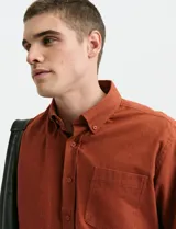 Camisa de franela lisa con cuello button-down, manga larga, botones al tono y bolsillo frontal en el pecho.