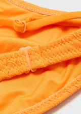 Top de bikini triangular color naranja con textura floral en relieve y tirantes finos regulables.