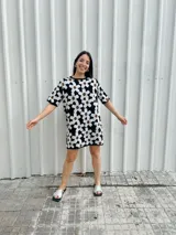 Vestido corto negro con estampado de flores blancas y marrones, de corte holgado y manga corta.