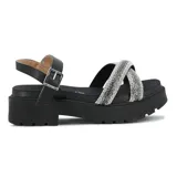 Sandalias de plataforma negra con suela dentada, tiras cruzadas en el empeine cubiertas de strass plateado y pulsera al tobillo con hebilla metálica.