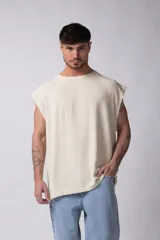 Musculosa oversize de tejido texturado color crema, con cuello redondo y terminaciones deshilachadas en las sisas. Presenta una costura central vertical en la espalda.