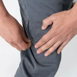 Pantalón utilitario gris con bajo ajustable a dos posiciones, bolsillos laterales y traseros.