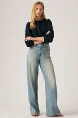 Jeans de corte recto y tiro alto, con diseño de pierna ancha y acabado lavado en tono celeste claro. Presentan cierre frontal con botón y cremallera, además de bolsillos laterales y traseros.