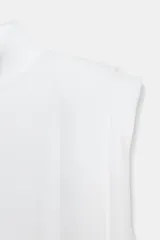Top de punto blanco sin mangas con cuello subido, hombreras marcadas y espalda descubierta con cierre de botones.