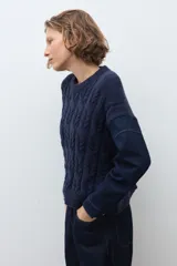 Sweater de punto trenzado en color azul marino, con cuello redondo y mangas largas. Presenta un diseño de tejido con textura en el frente y mangas lisas.