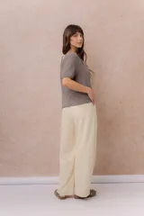 Buzo de tejido liviano y delicado color marrón topo, con textura suave y sutil transparencia, diseño de calce relajado, escote en V y mangas cortas.