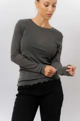 Remera de manga larga en tejido liviano y translúcido color gris oscuro, con cuello redondo y terminaciones onduladas en ruedo y puños.