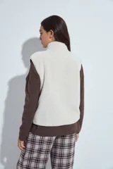 Chaleco de corderito color marrón oscuro, con cierre frontal completo, cuello alto y bolsillos laterales.