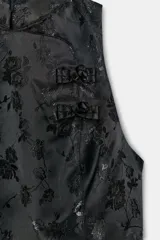 Top negro de tejido jacquard con estampado floral tono sobre tono, cuello redondo y diseño sin mangas. Presenta cierre frontal con alamares y cierre trasero con cremallera oculta.