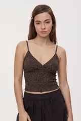 Top de calce ajustado con escote en V cruzado, breteles finos y estampado animal print. Presenta detalles de encaje en los bordes del escote.