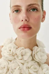 Top corto de cuello halter, confeccionado con una estructura de tejido que forma flores en relieve por toda la prenda. Presenta cierre en la espalda con abertura y botón oculto.